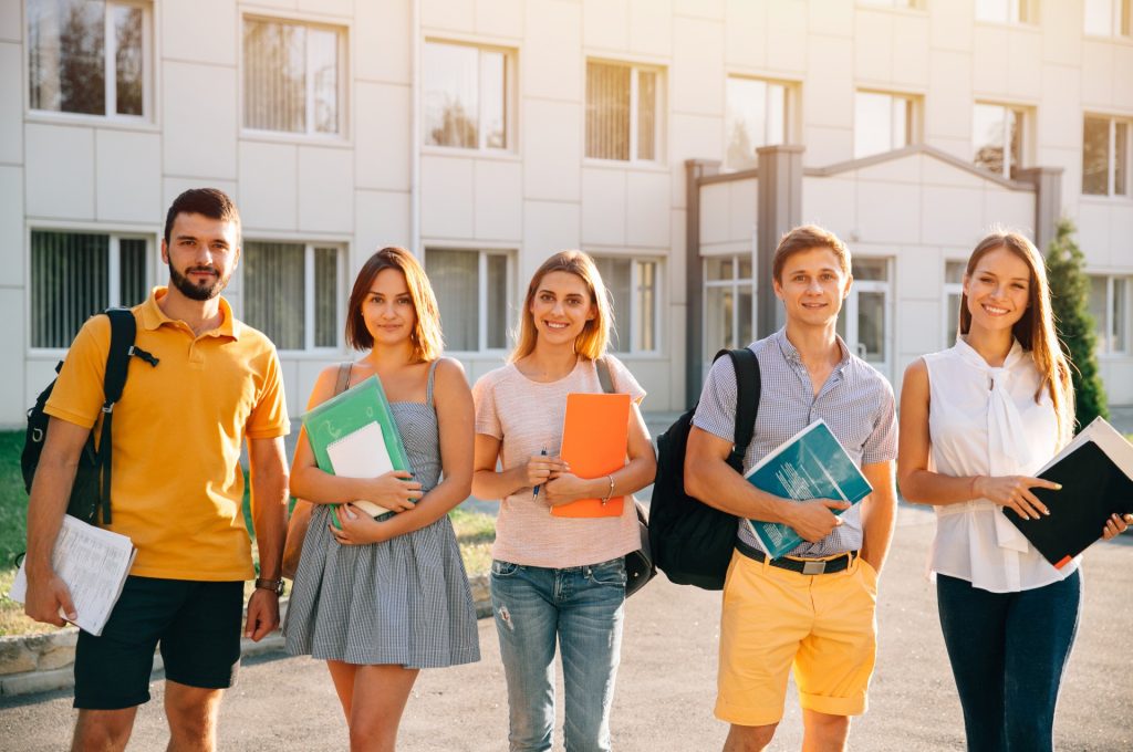 portrait_group_happy_students_casual_outfit_with_books_while_standing